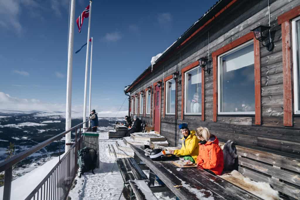 Utsikt över Funäsdalen fjällen och skidåkare som njuter av fjällsemestern på en väderbiten terrass med snö, perfekt för skidåkning och fjällresor i svenska fjällen.
