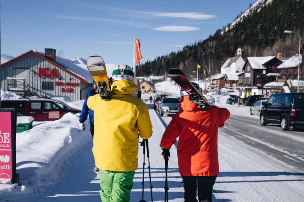 Fjällvärlden i Funäsdalen med skidåkare på vinterpromenad, snötäckta hus och klarblå himmel, perfekt för fjällsemester och skidade runt i fjällen.